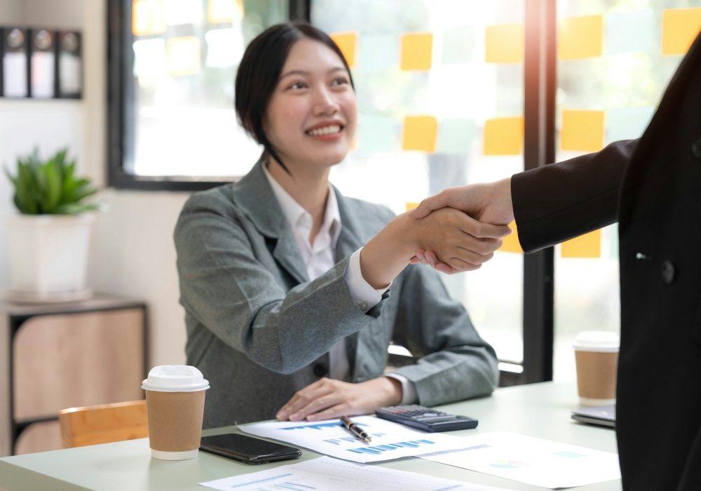 Two Asian businesswomen are shaking hands in the office. business cooperation, business dealing